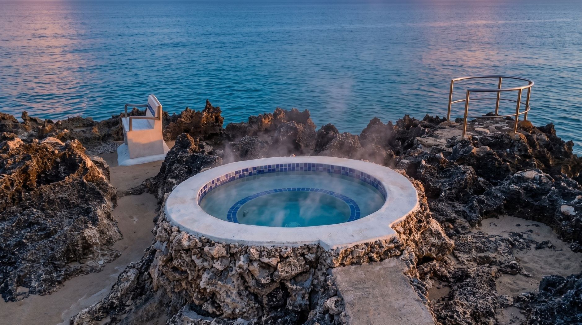 Steaming tiled soaking pool set among rocks beside the ocean