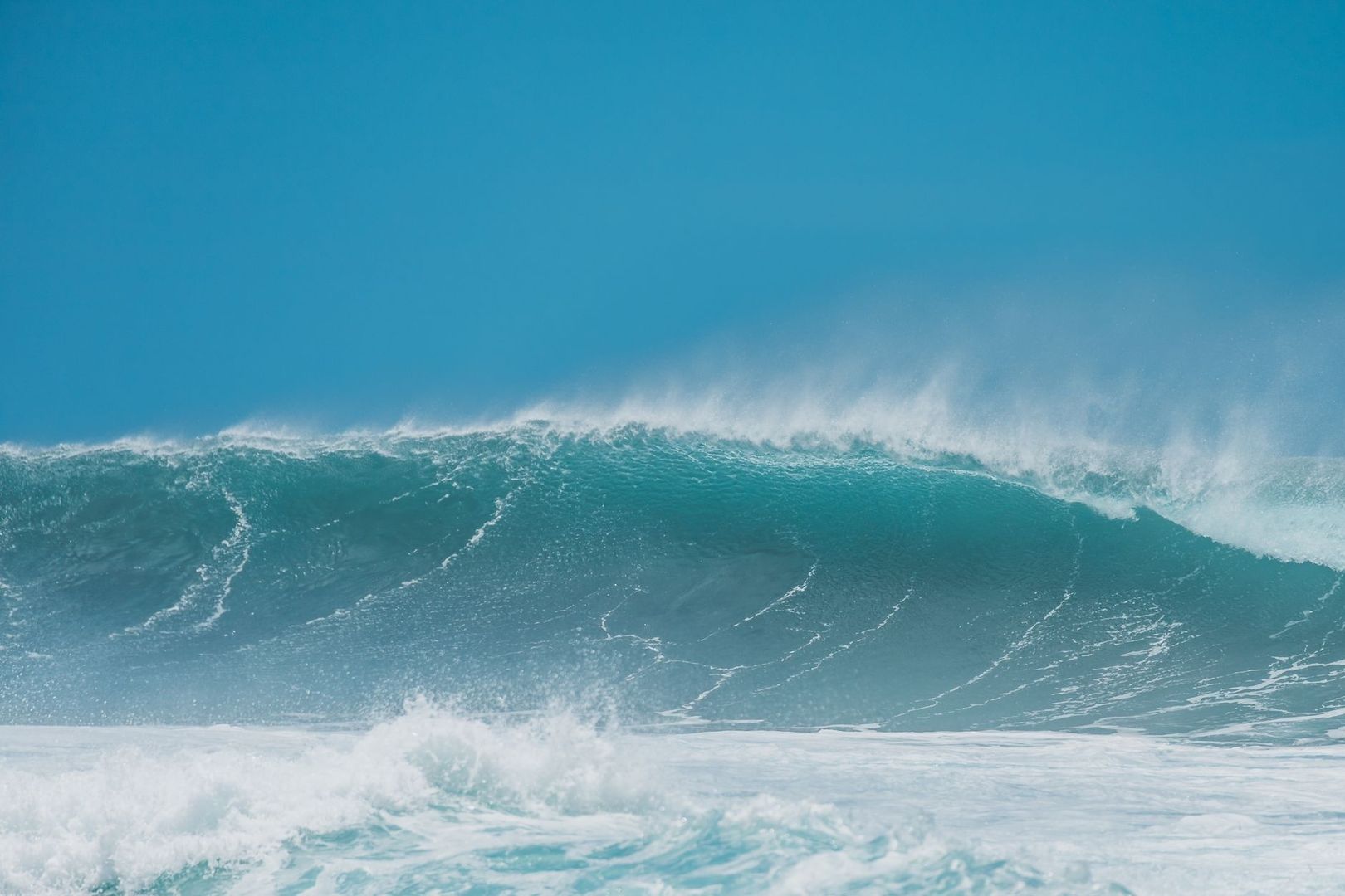 Large blue ocean swell breaking with windblown spray and white foam