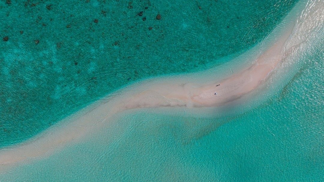 Aerial view of a pale sandbar curving through turquoise ocean water
