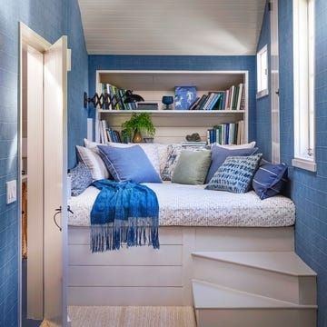 Coastal-style window seat with blue cushions, books, and built-in shelves